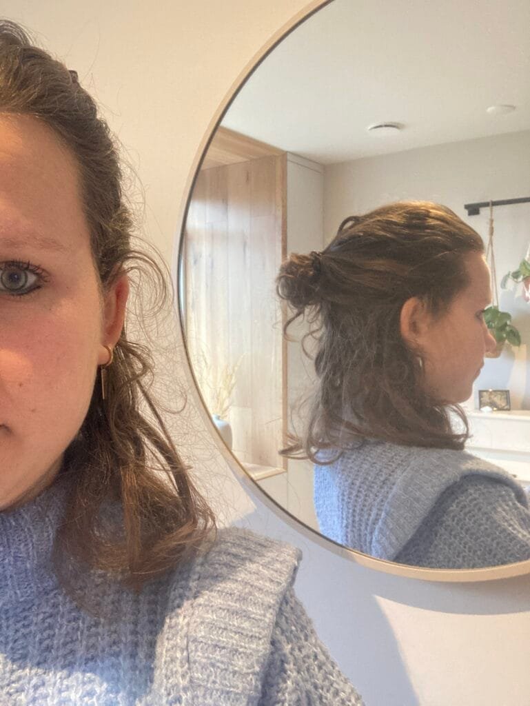 Vrouw kijkt in de spiegel tijdens reflectie over verbinding in relaties en het loslaten van het perfecte huwelijk.